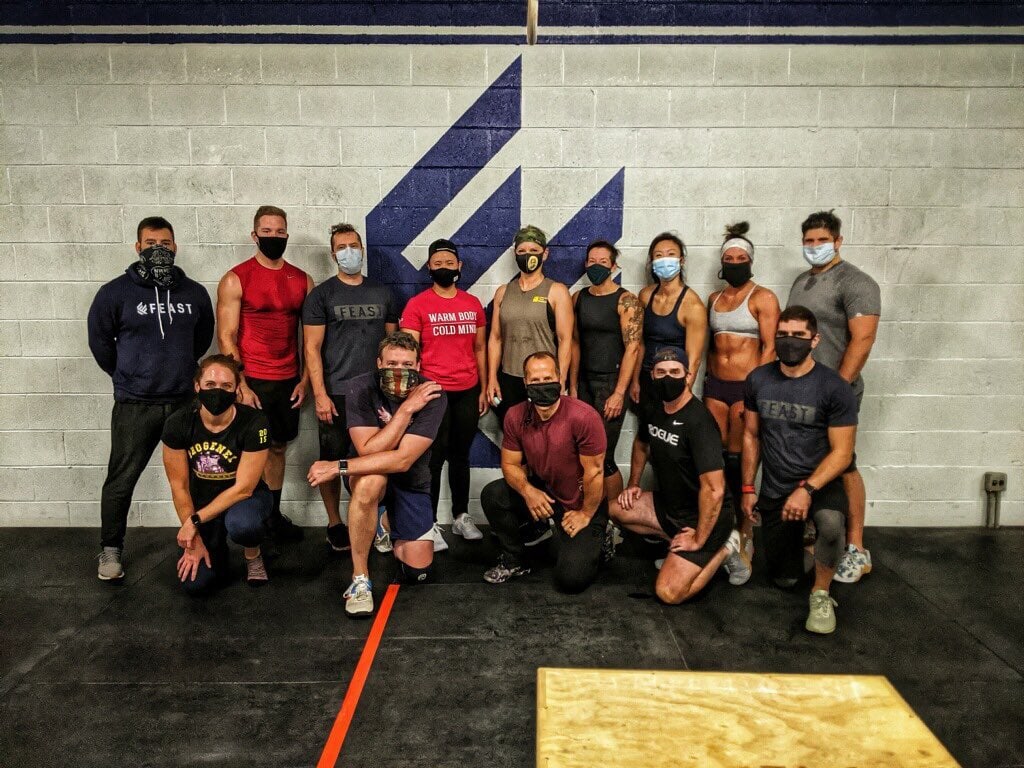 A group picture of the team from Feast Fitness, posing in their space while wearing face masks