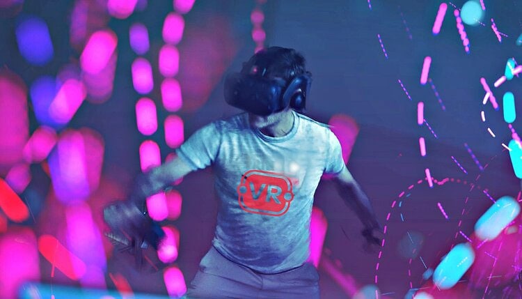 A picture of a person exercising surrounded by purple lights, in a VR headset and wearing a Redline VR tshirt