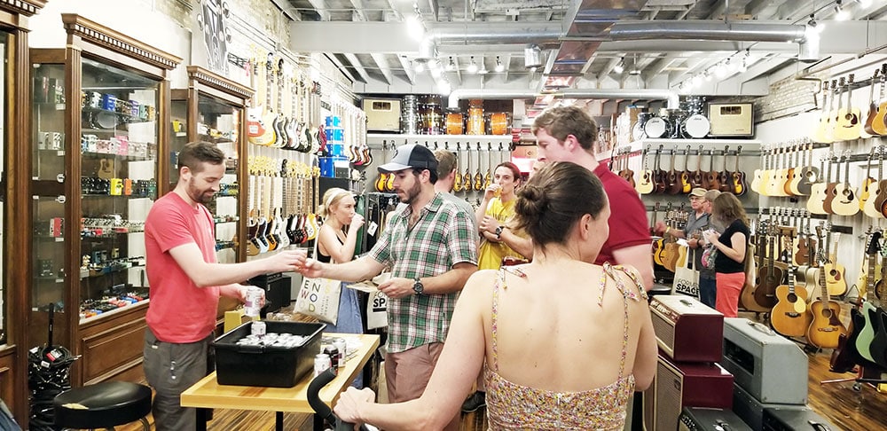 Jacob from Empirical Brewery offers a tasting glass full of beer to a guest at Malt Row on Damen