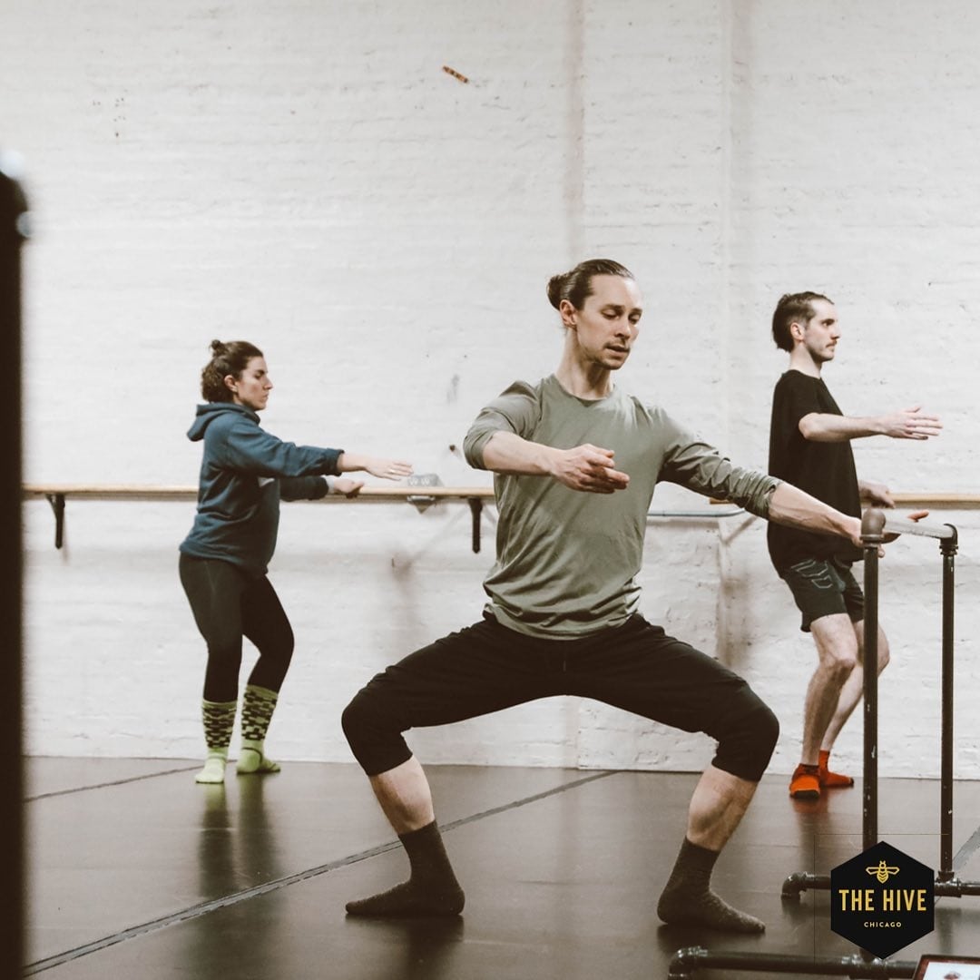 An instructor teaches youth students ballet in a chic industrial studio