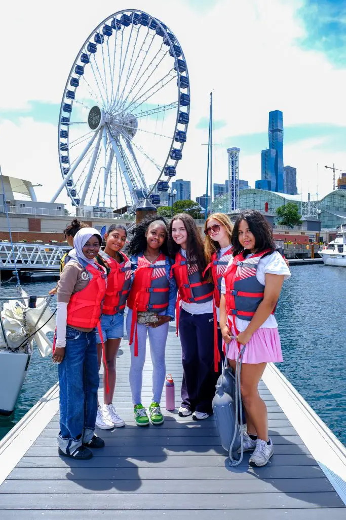 Sail Her Dreams students pose in life vests on the harbor 